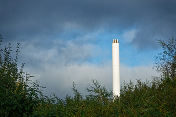 White industrial exhaust tower Flensburger Stadtwerke rising over plants to sky