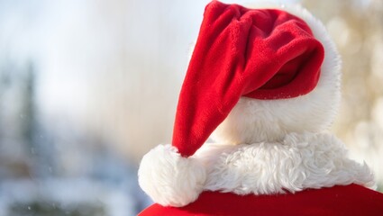Santa claus wearing his iconic red velvet hat and furry white trim, standing from a back view, representing the joy and anticipation of christmas and festive winter holidays