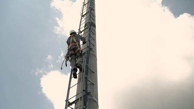 Telecommunication worker climbing cell tower with safety harness