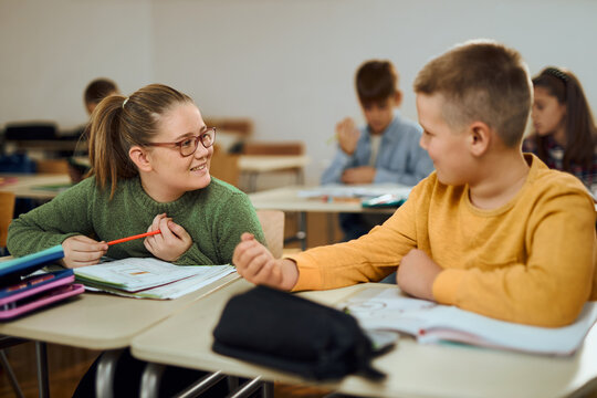 Happy elementary students talking about something funny on a class in the classroom.