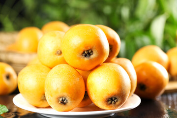 Fresh Loquat Fruits on Plate - Golden Orange Asian Stone Fruit Display with Natural Green Background
