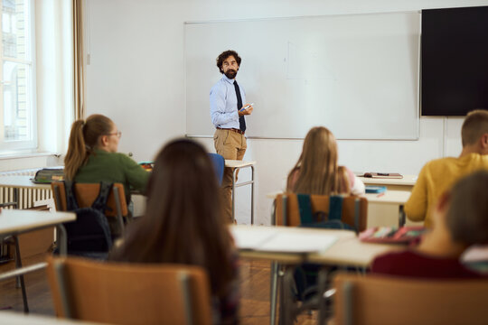 Elementary teacher talking to his students about math during a class at elementary school