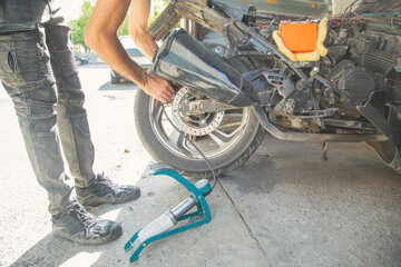 Man inflating motorcycle tire with a air pump.