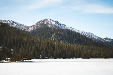 Frozen lake Lognvikvatn surrounded by golden spring fields and distant snowy peaks, Norway. Beautiful contrast of seasons and pure northern landscape