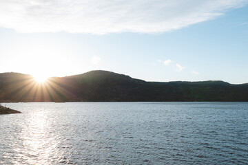 Golden light over calm lake in Setesdal Valley, Norway. Gentle hills and still water reflect warm sunset tones, capturing peaceful essence of Norwegian wilderness