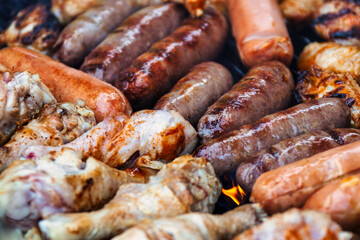 grilling chicken drumsticks ad sausages on the barbeque outdoors at a picnic