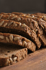 Slices of brown bread with sunflower seeds on wooden table.