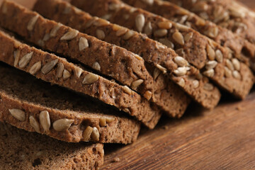 Sliced bread with sunflower seeds on wooden table, closeup.