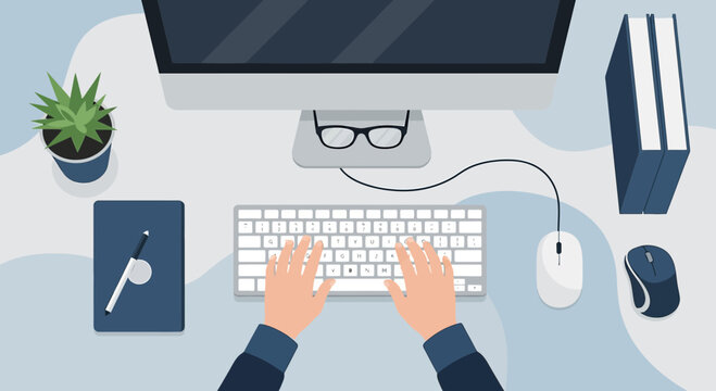 Overhead view of a person working at a clean desk with a computer and office supplies