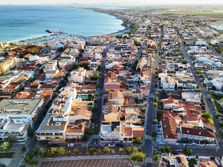 Drone view of Torre de la Horadada, picturesque coastal town on Spain Mediterranean coast, view to residential areas, marina, sandy beaches, and calm blue sea waters under evening light. Costa Blanca