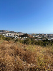 A view of a town in a mountain valley from a hill with parched grass during a drought, under a clear blue cloudless sky. Spain, early autumn.