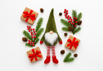 Flat lay Christmas composition with cute gnome, pine branches, red berries, cones, and gift boxes on white background. Festive holiday decoration in Scandinavian style.