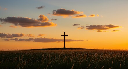 Obraz premium A simple cross stands alone on a grassy hill at sunset. The sky glows with warm orange and golden tones as clouds drift above. Perfect for faith themes, spiritual concepts, or memorial designs.