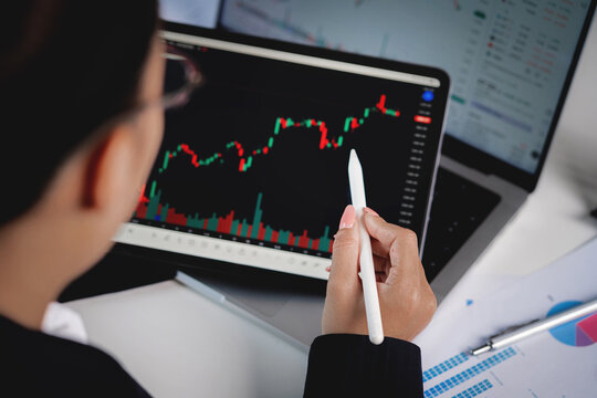 A woman is using a pen to draw a graph on a computer screen