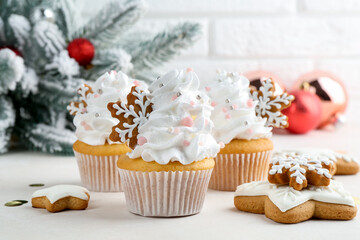 Tasty cupcakes with Christmas decor and gingerbread cookies on white table, closeup