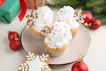 Tasty cupcakes with Christmas decor and gingerbread cookies on white table, closeup