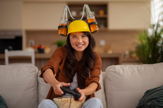Woman playing video games with beer helmet and popcorn