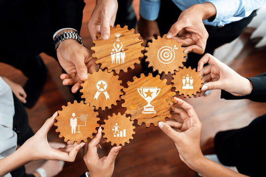 Fototapeta This image captures hands collaborating over wooden gears, each featuring success and teamwork icons, symbolizing unity in achieving business goals and recognition. Amity