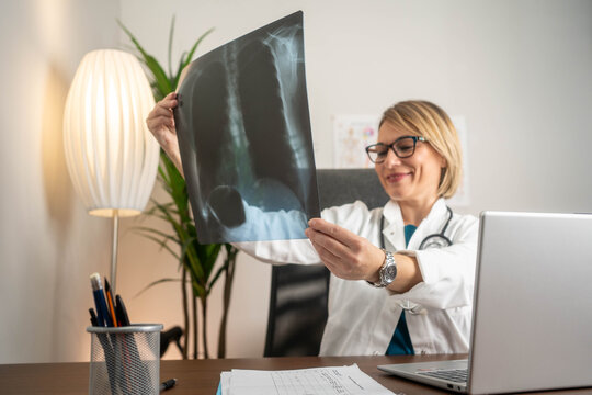 Confident female doctor examining lung X-ray in medical office