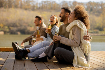 Friends celebrating joyfully by the river on a sunny autumn afternoon
