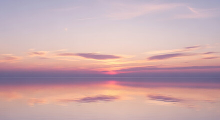 Fototapeta premium Soft pastel sunset over calm water reflecting the sky with clouds in shades of pink and purple hues
