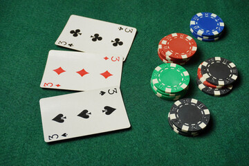 Chips are scattered around, and the three cards are a mix of suits and values, indicating active bets and future winnings