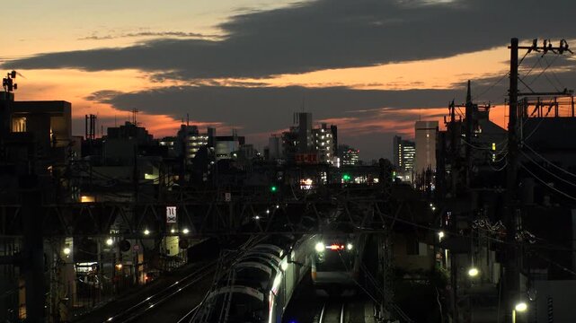 TOKYO, JAPAN - JUL 2025 : Breathtaking sunset over a railway in a Tokyo residential area. A train arriving at the station during the golden hour, showcasing the daily commuter life.