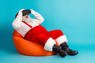 Santa in virtual reality relaxes on an orange chair with a blue backdrop enjoying a festive Christmas moment for holiday marketing and seasonal promotions