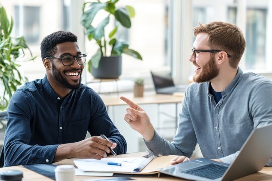 African American and Caucasian professionals collaborating at an office table, smiling while reviewing data in a modern business environment.