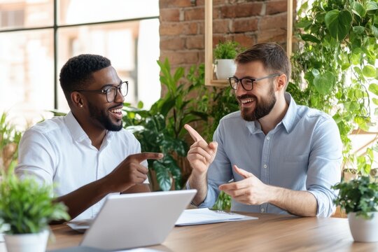 African American and Caucasian professionals collaborating at an office table, smiling while reviewing data in a modern business environment.
