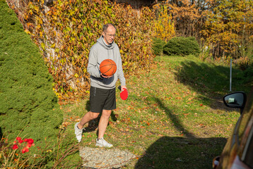 osoba w stroju sportowym idąca z piłką do koszykówki oraz rakietkami do ping ponga © siwyk