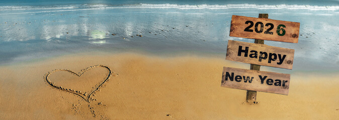 2026 happy new year writted on a wooden signpost on a beach and heart drawing on the sand in front of the sea