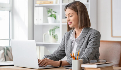 Young businesswoman using laptop in office