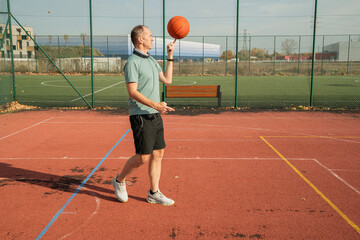 osoba rzuca, bawi się piłką do koszykówki na boisku na zewnątrz w słoneczny dzień © siwyk