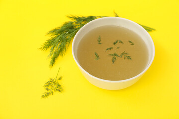 Bowl of tasty vegetable broth on yellow background