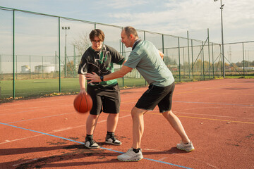 Dwie osoby grające w koszykówkę na zewnętrznym boisku w słoneczny dzień © siwyk