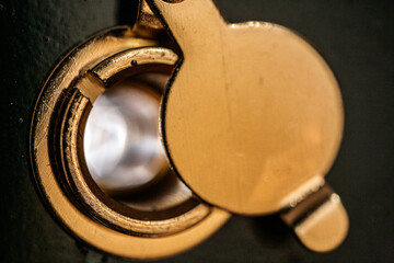 Close-up view of a well-maintained peephole on a black door