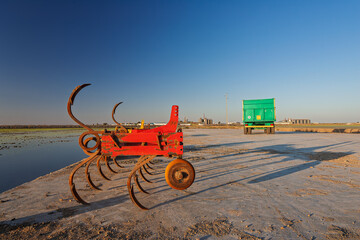 Rusty tilling implement against the backdrop of flooded rice fields