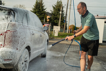 mężczyzna myjący samochód na myjni samoobsługowej