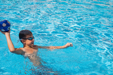 young athletic boy playing ball in the pool