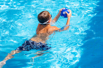 young athletic boy playing ball in the pool