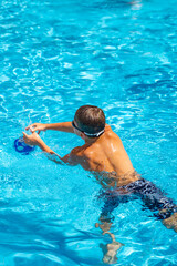young athletic boy playing ball in the pool