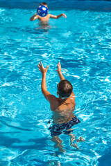 young athletic boy playing ball in the pool