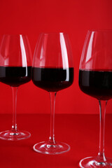 Glasses of red wine on color background