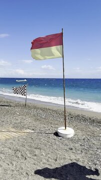 Flags in the wind, fluttering flags in a strong sea breeze in sunny weather on the shore of a seaside resort