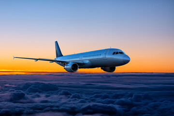 Naklejka premium Passenger airplane is flying in the sunset sky