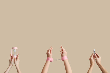 Female hands with hourglass, handcuffs and butt plug on beige background