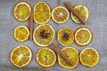 Dried orange slices, cinnamon sticks and star anise arranged on burlap background, natural Christmas decoration, aromatic spices.