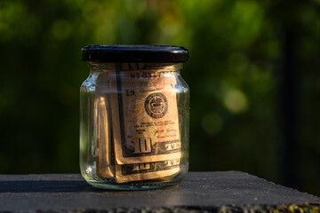 US dollar banknote saving money in glass jar. Consumption and economy