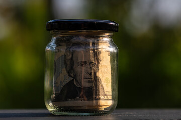 US dollar banknote saving money in glass jar. Consumption and economy